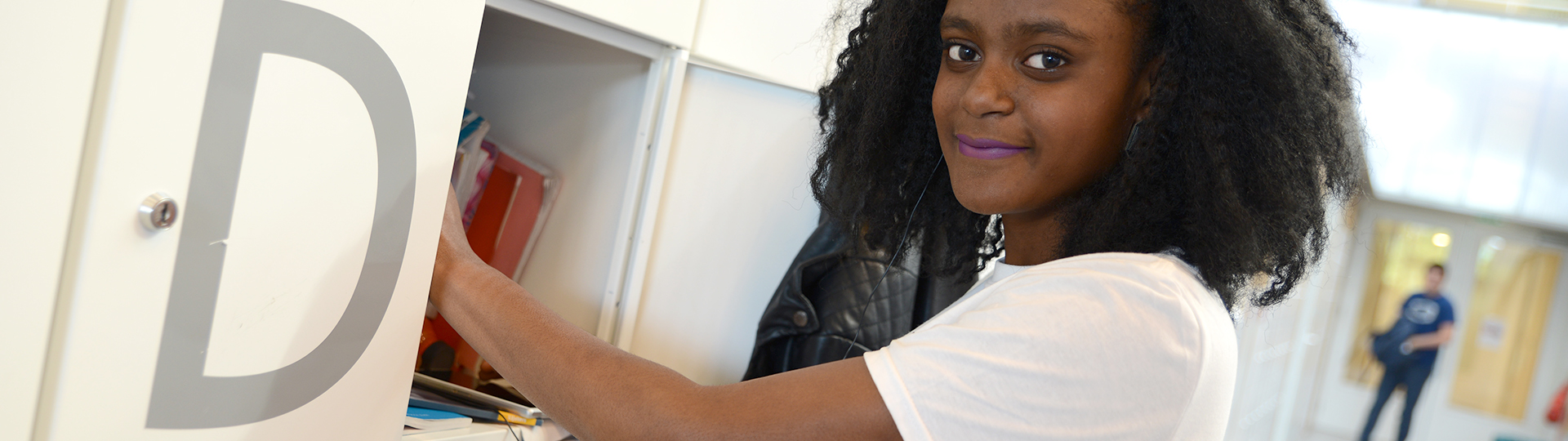 Student reikt in haar kluisje om iets te pakken terwijl ze een foto laat maken.