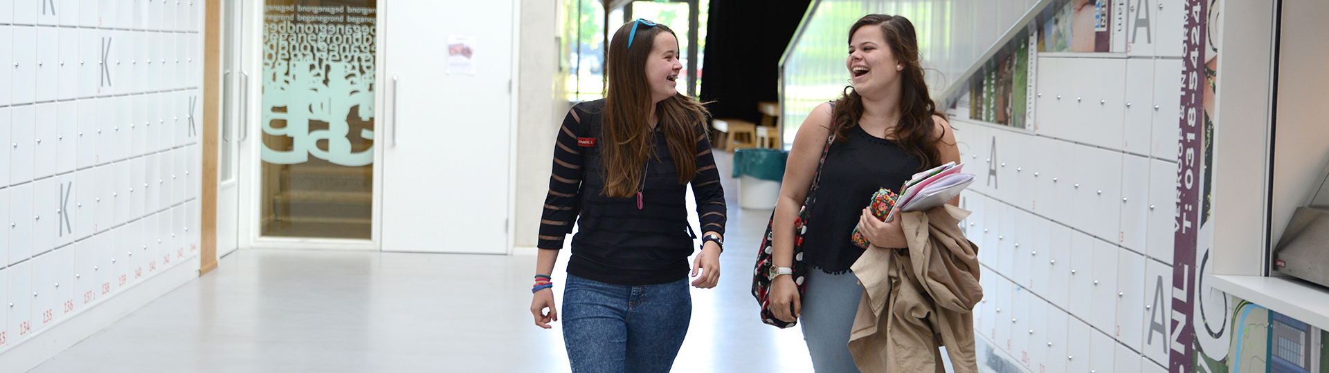 Studenten bij witte kluisjes aan het lachen in de hal