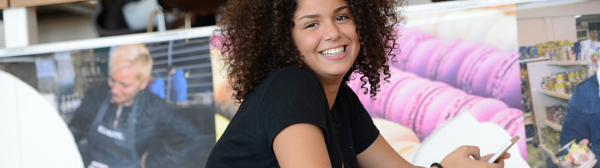 Lachende student tijdens de les met een poster over macrons op de achtergrond. Overstapcoach